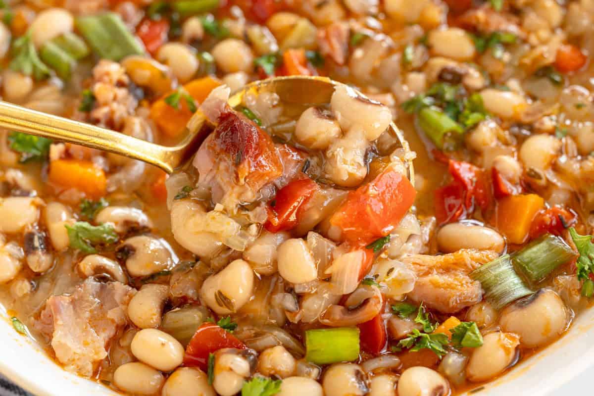 A spoonful of hearty Black-Eyed Pea Soup with vegetables and herbs.