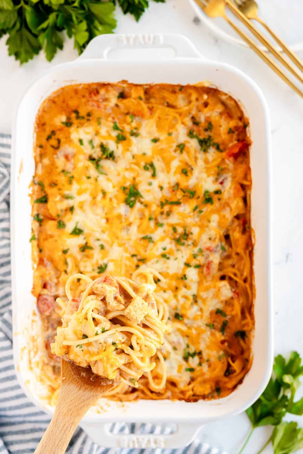 a large casserole dish with chicken spaghetti being spooned out.