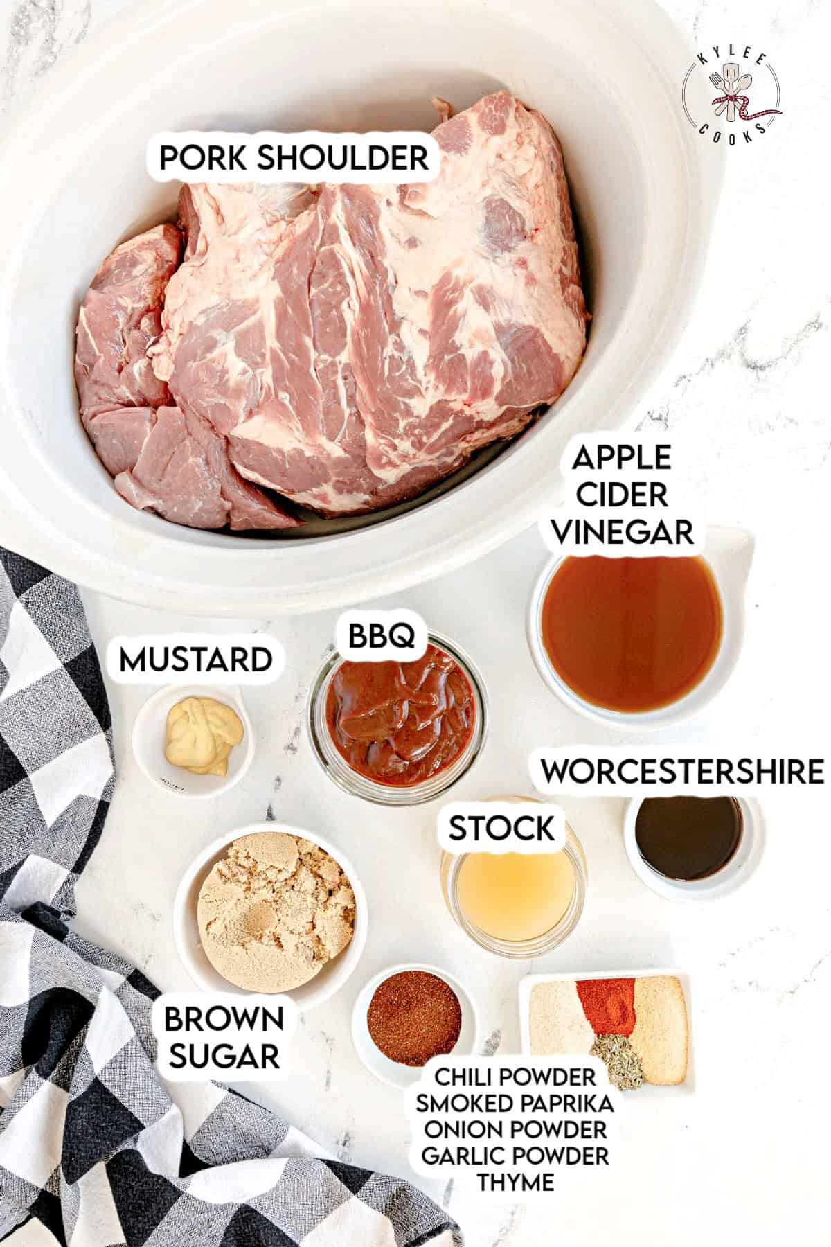 Ingredients for a pork shoulder recipe arranged on a table, including pork shoulder, apple cider vinegar, mustard, BBQ sauce, Worcestershire sauce, stock, brown sugar, and various spices.