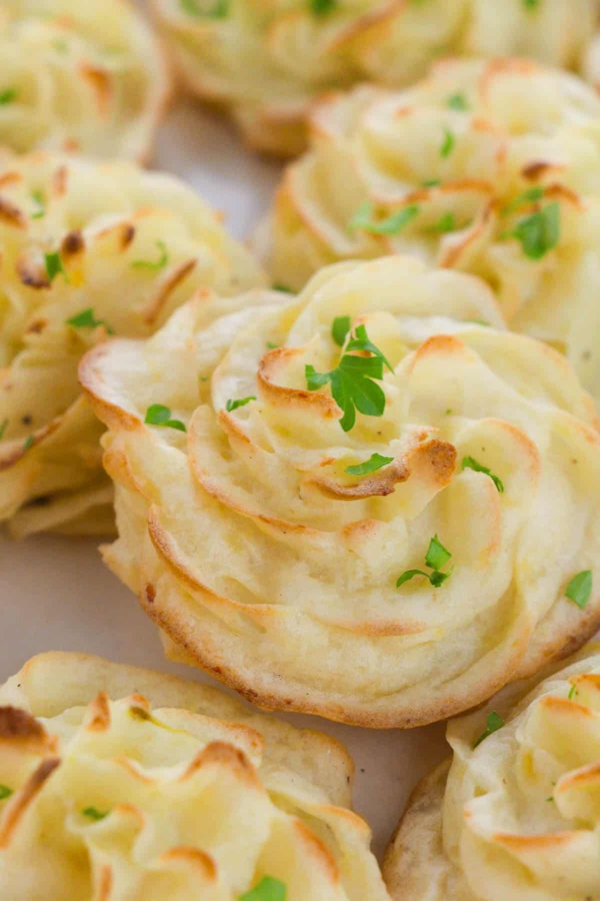 Close-up of baked duchess potatoes with browned edges and parsley.
