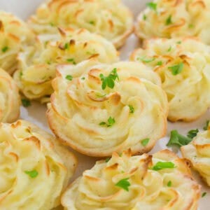 Swirled portions of golden baked duchess potatoes topped with parsley.
