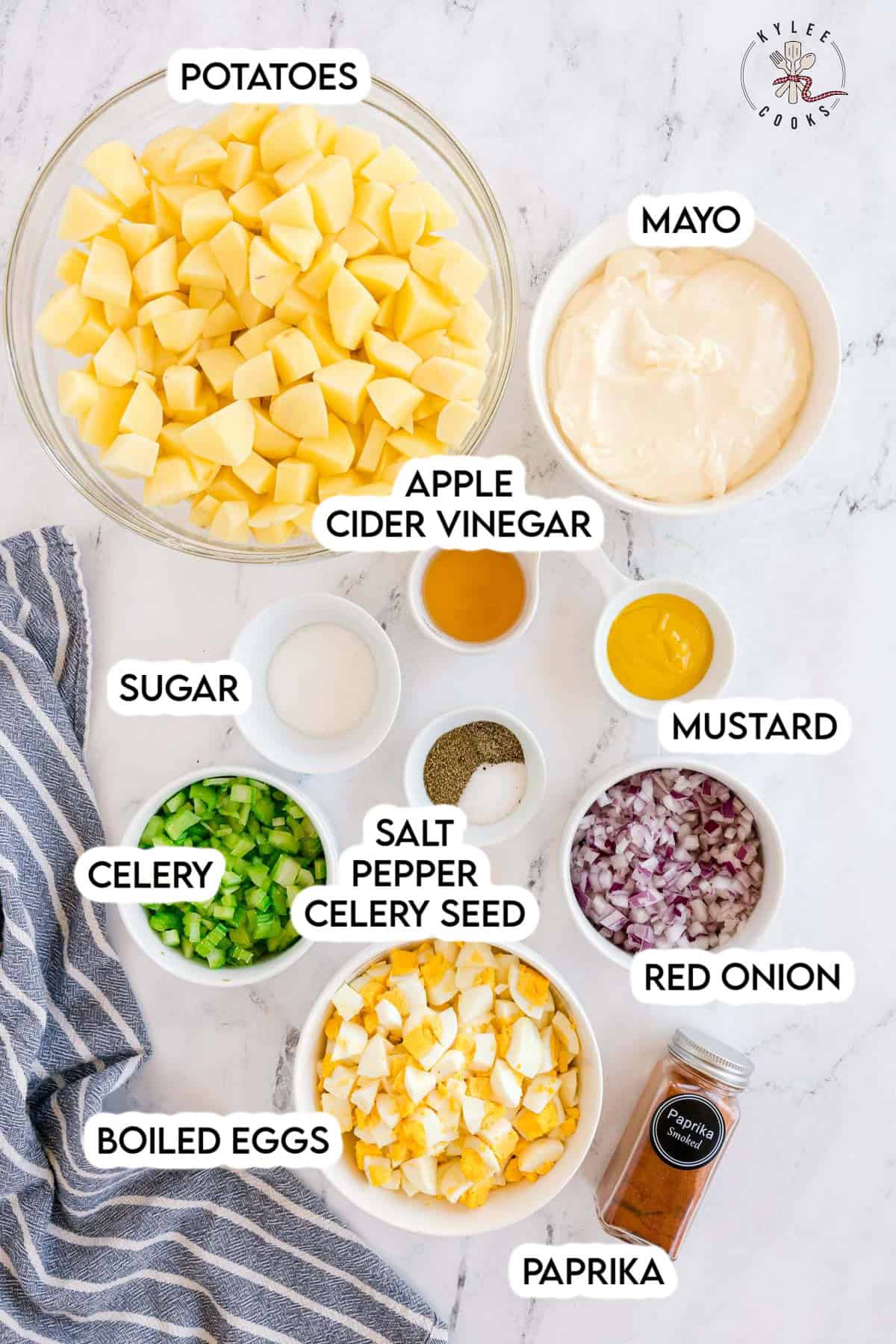 Ingredients for potato salad laid out in bowls, including potatoes, mayo, mustard, vinegar, sugar, celery, red onion, boiled eggs, paprika, salt, pepper, and celery seed. Text on the image labels each ingredient.