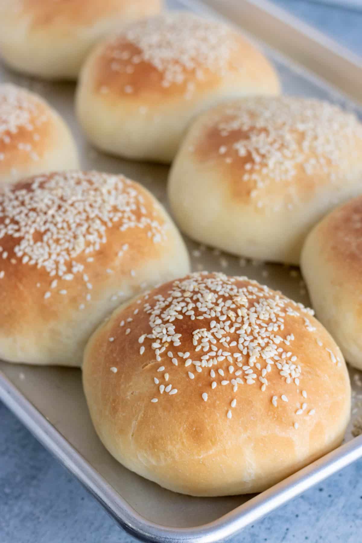 Homemade hamburger buns on a baking sheet