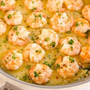 Cooked shrimp in a garlic butter sauce topped with parsley.