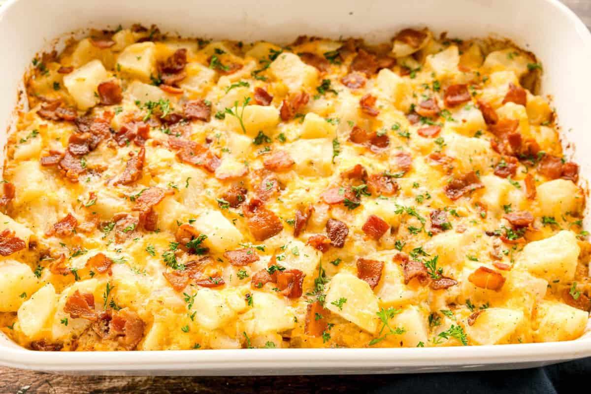 A baking dish filled with baked potato casserole topped with bacon and herbs.