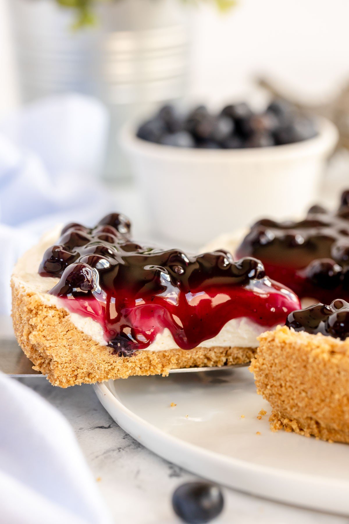 No bake cheesecake on a white plate with a platter of cheesecake