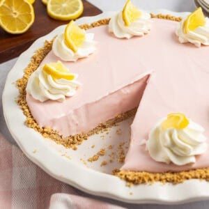 A close-up of the pink lemonade pie with a crumb crust and whipped cream topped with lemon slices.