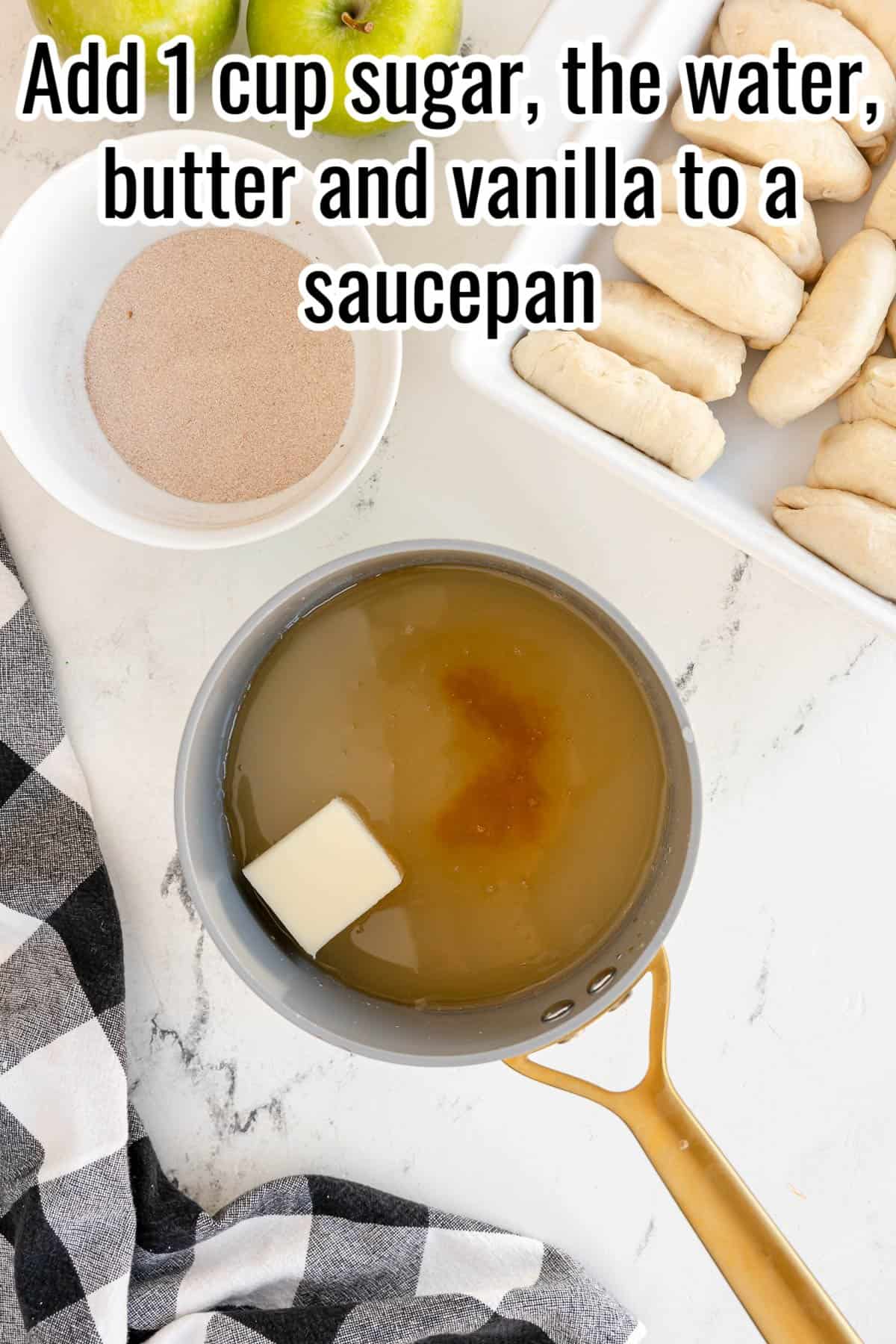 A saucepan containing water, sugar, butter, and vanilla sits on a countertop with a bowl of sugar and a tray of dough nearby. The text over the image says, "Add 1 cup sugar, the water, butter, and vanilla to a saucepan.
