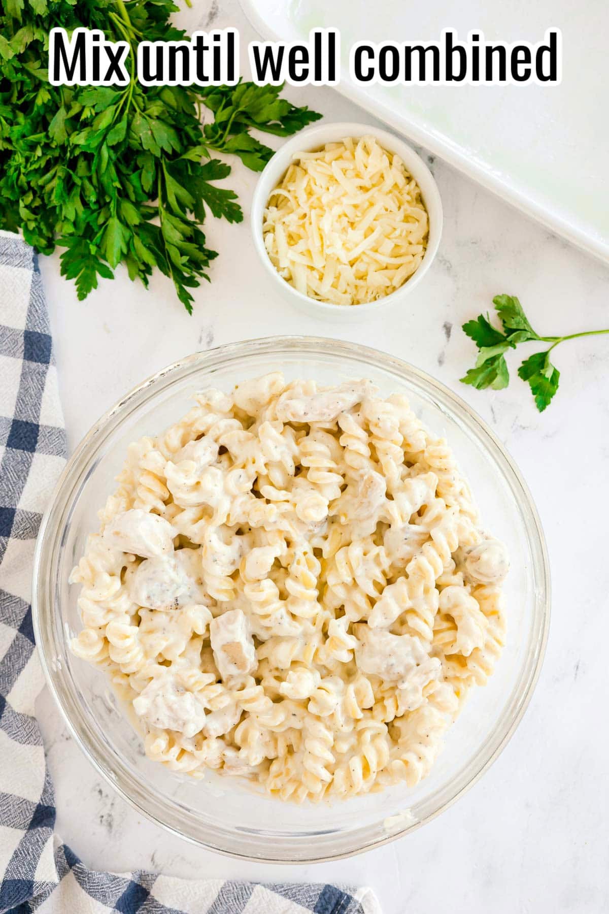 A bowl of rotini pasta and chicken coated in Alfredo sauce. Text on the image says 'Mix until well combined'.