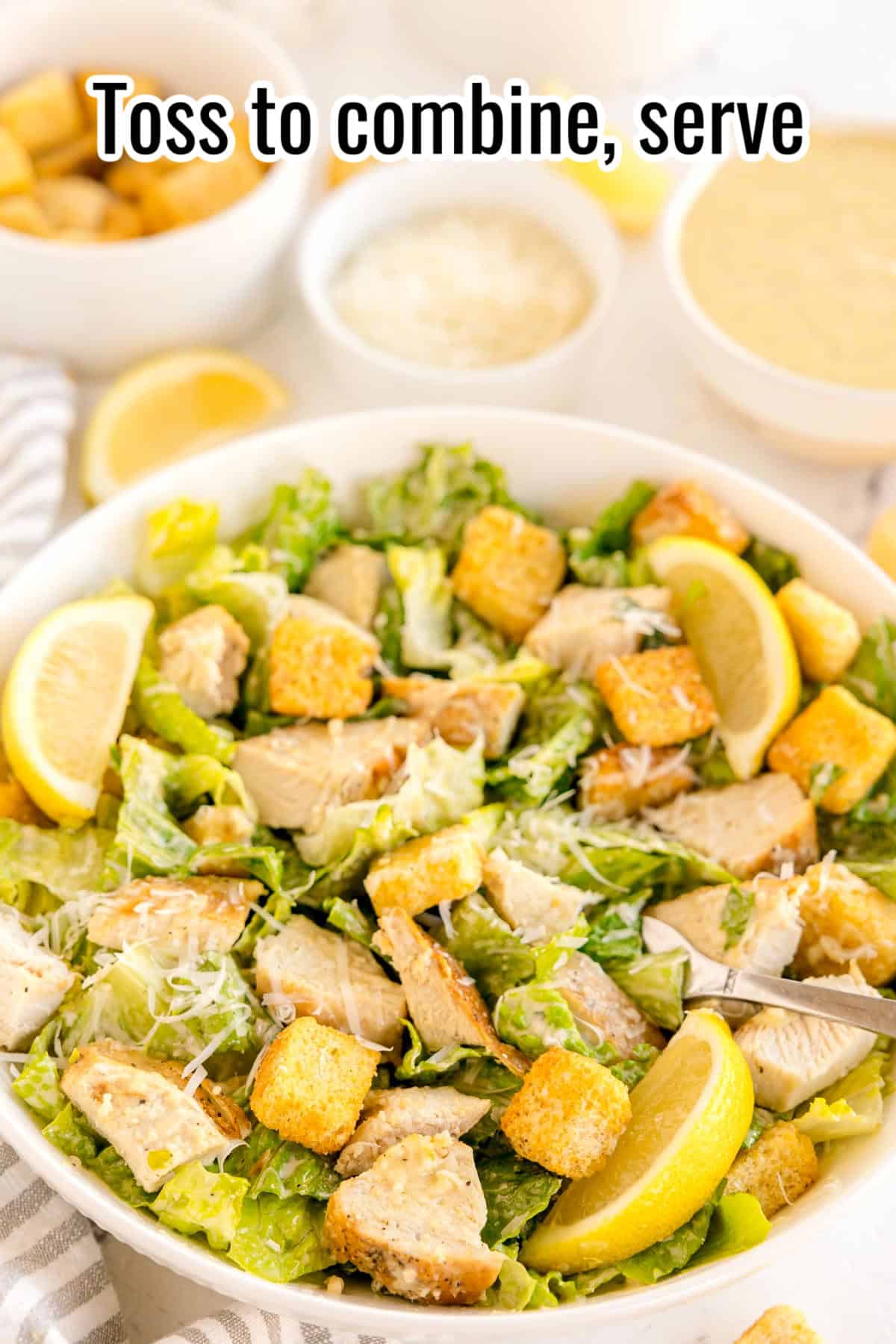 Finished Caesar salad tossed with dressing, chicken, croutons, and lemon wedges. Text on the image says 'Toss to combine, serve'.