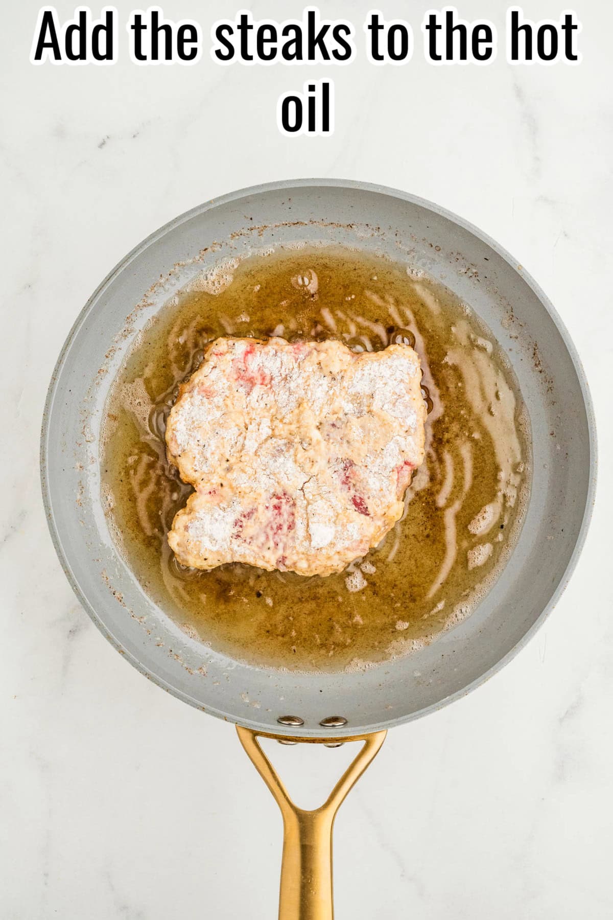 Breaded steak in hot oil in a skillet. Text on the image says 'Add the steaks to the hot oil'.