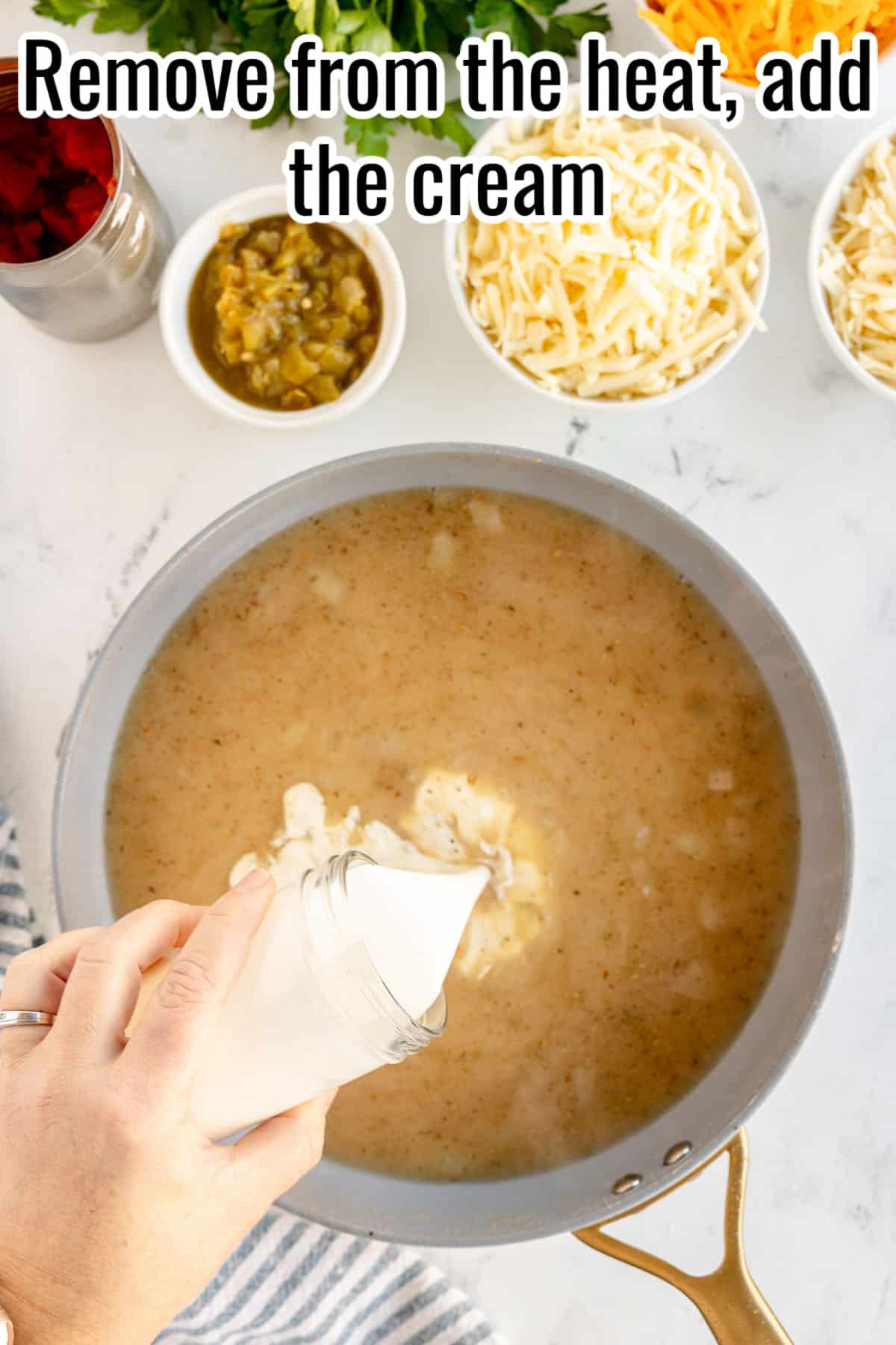 A person pouring cream into a pot of sauce.