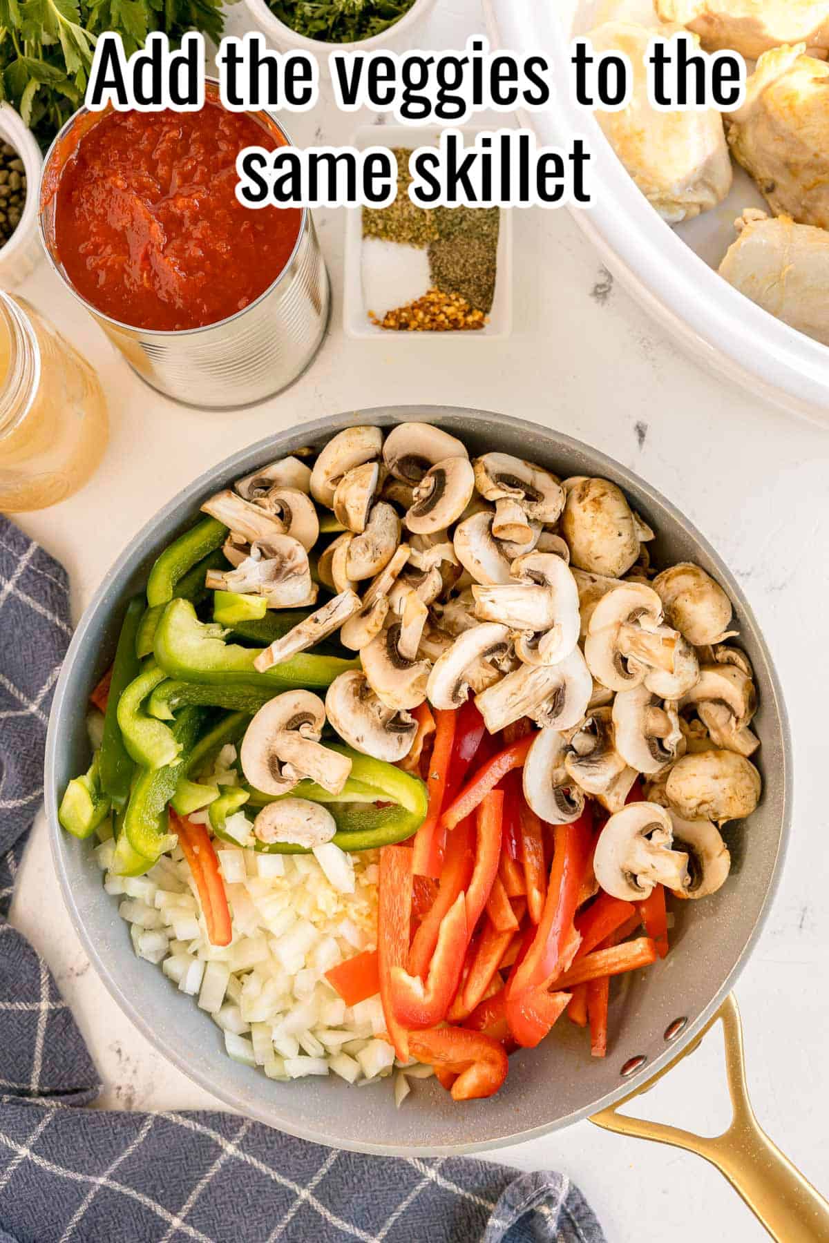 A skillet filled with chopped onions, garlic, sliced mushrooms, and bell peppers, ready to be cooked, with a text overlay that reads "Add the veggies to the same skillet."
