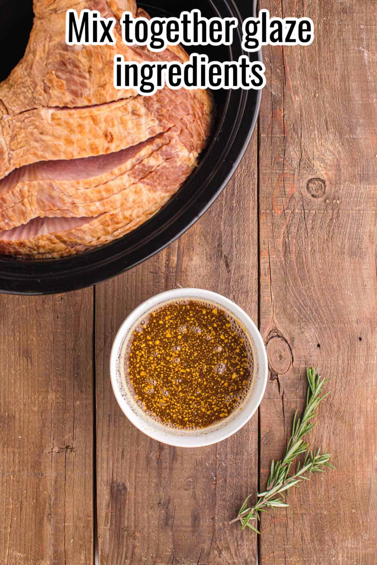 Bowl of glaze ingredients next to a raw ham in a slow cooker.