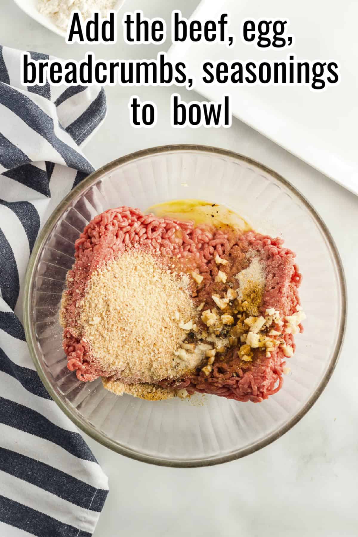 A glass bowl filled with ground beef, breadcrumbs, egg, garlic, and seasonings, with text overlay reading "Add the beef, egg, breadcrumbs, seasonings to bowl."