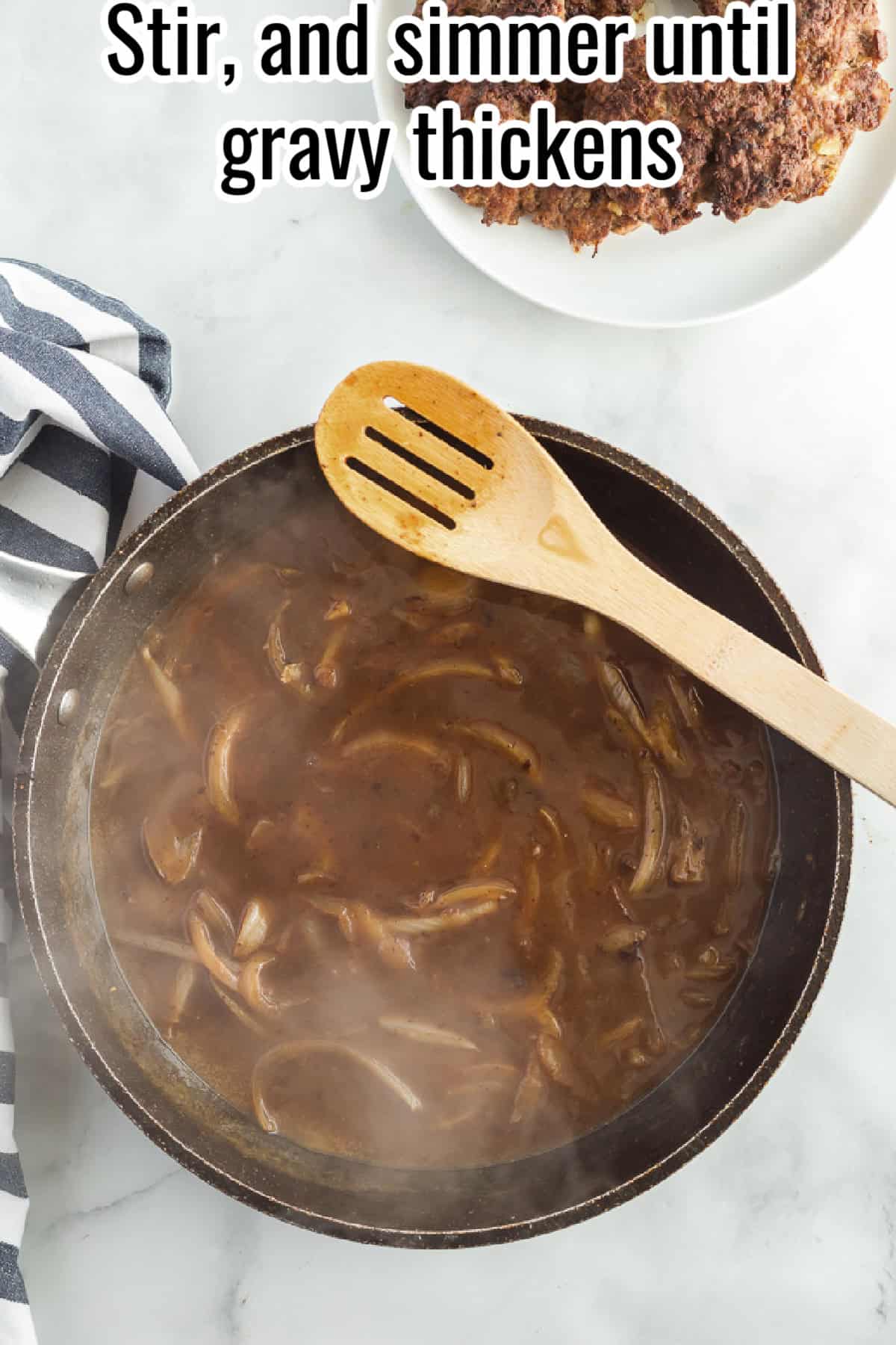 A steaming skillet filled with thickened onion gravy, stirred with a wooden spoon, with text overlay reading "Stir, and simmer until gravy thickens."