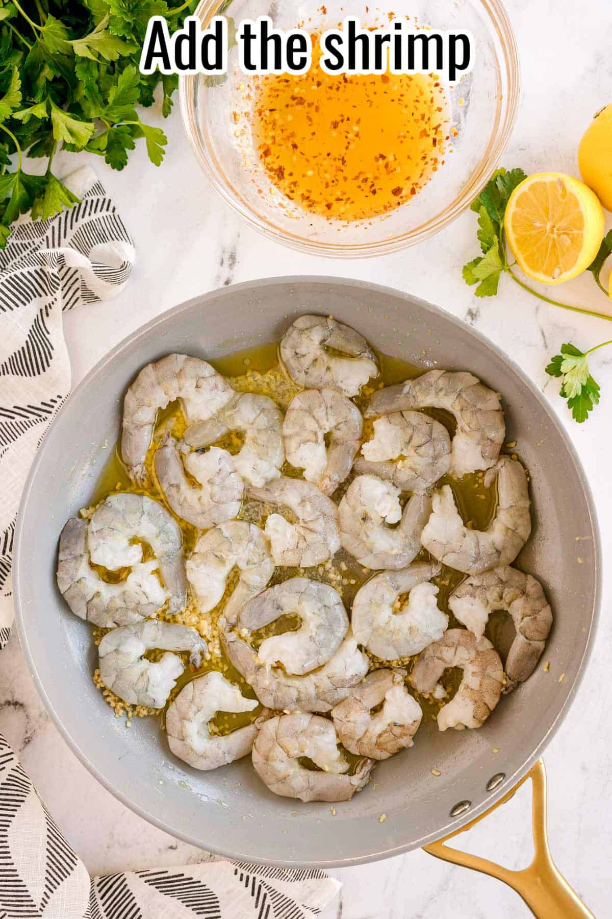 Raw shrimp cooking in a pan with garlic and oil. Text on the image says 'Add the shrimp'.