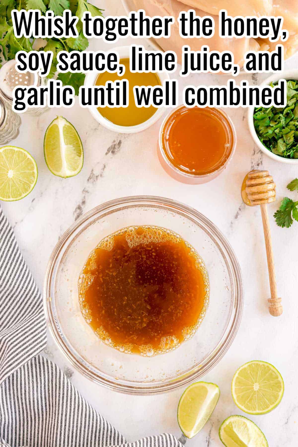 A bowl of honey lime sauce surrounded by limes, garlic, honey, and herbs. Text on the image says 'Whisk together the honey, soy sauce, lime juice, and garlic until well combined'.