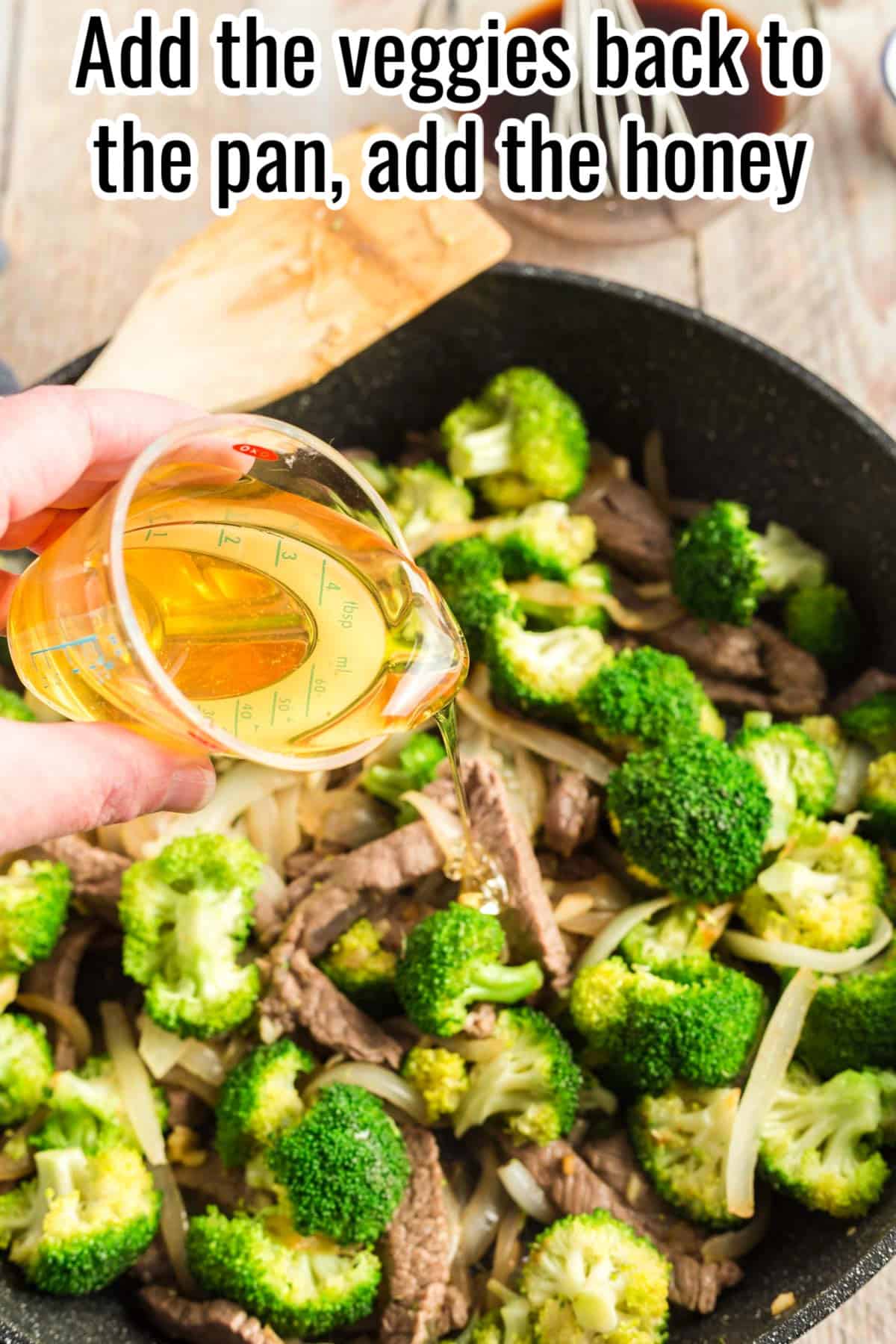 A hand pouring honey into a skillet filled with cooked beef, onions, and broccoli. Text on the image says 'Add the veggies back to the pan, add the honey'.