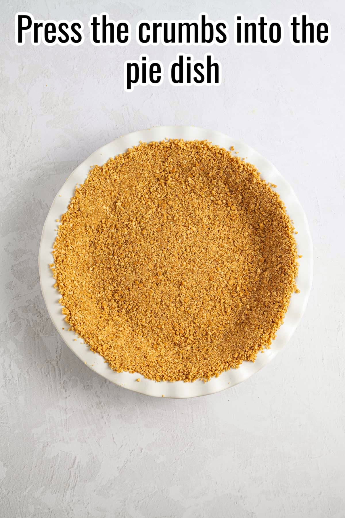 Crumb crust pressed into a white pie dish, with text that says 'Press the crumbs into the pie dish'.
