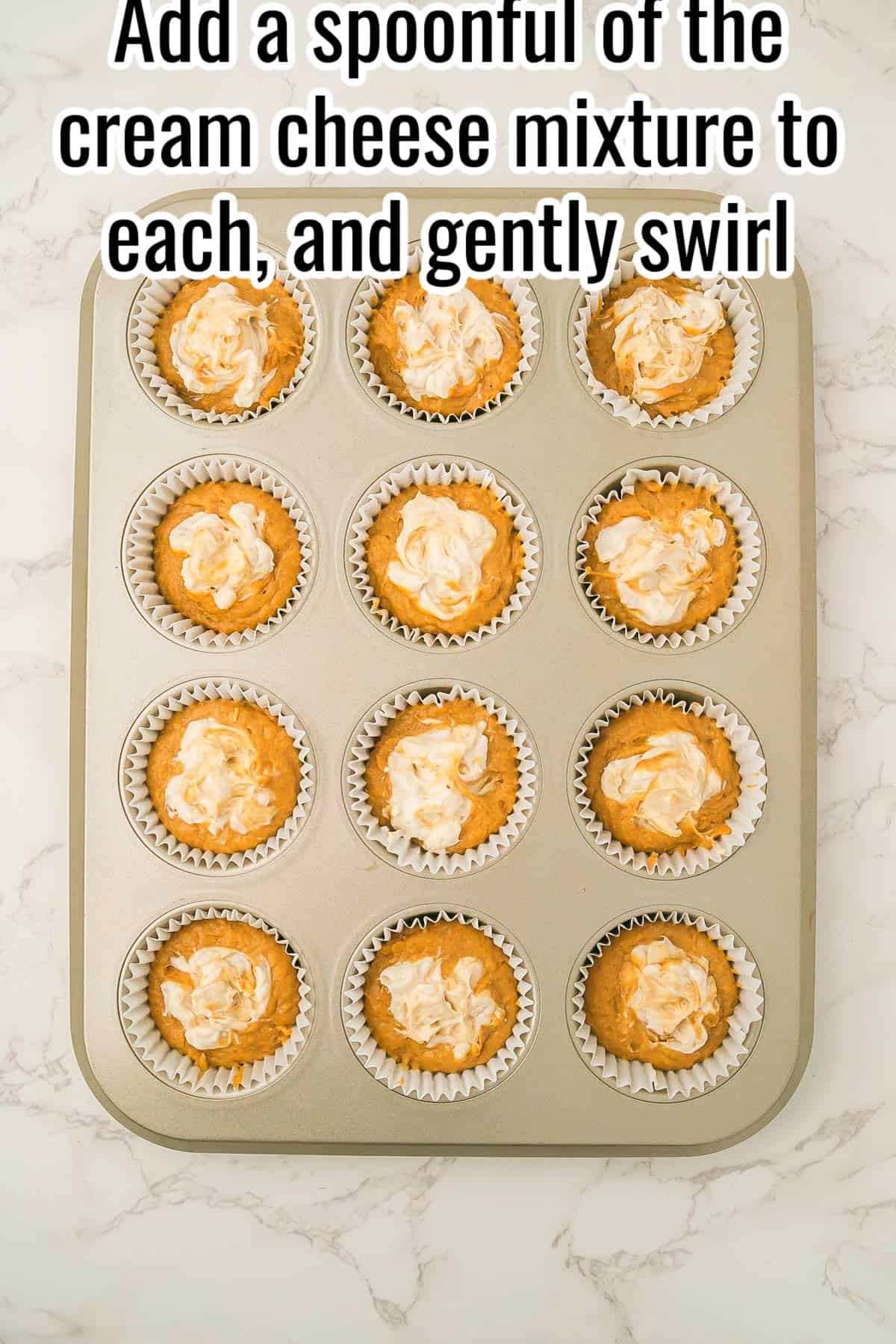 Muffin tin filled with pumpkin batter topped with cream cheese swirls. Text on the image says 'Add a spoonful of the cream cheese mixture to each, and gently swirl'.