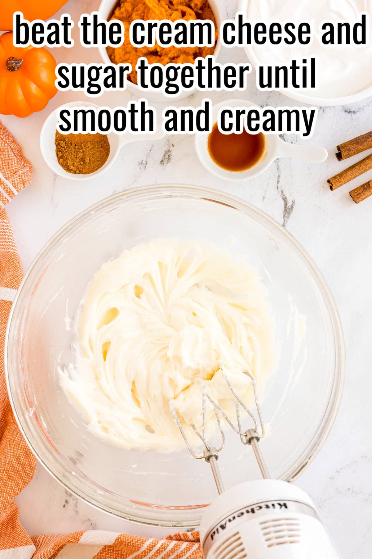 A glass bowl with cream cheese and sugar beaten until smooth and creamy. Text on the image says 'beat the cream cheese and sugar together until smooth and creamy'.