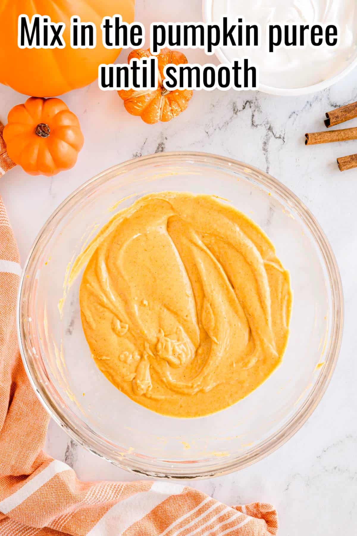 A glass bowl with pumpkin puree mixed into the cream cheese mixture until smooth. Text on the image says 'Mix in the pumpkin puree until smooth'.