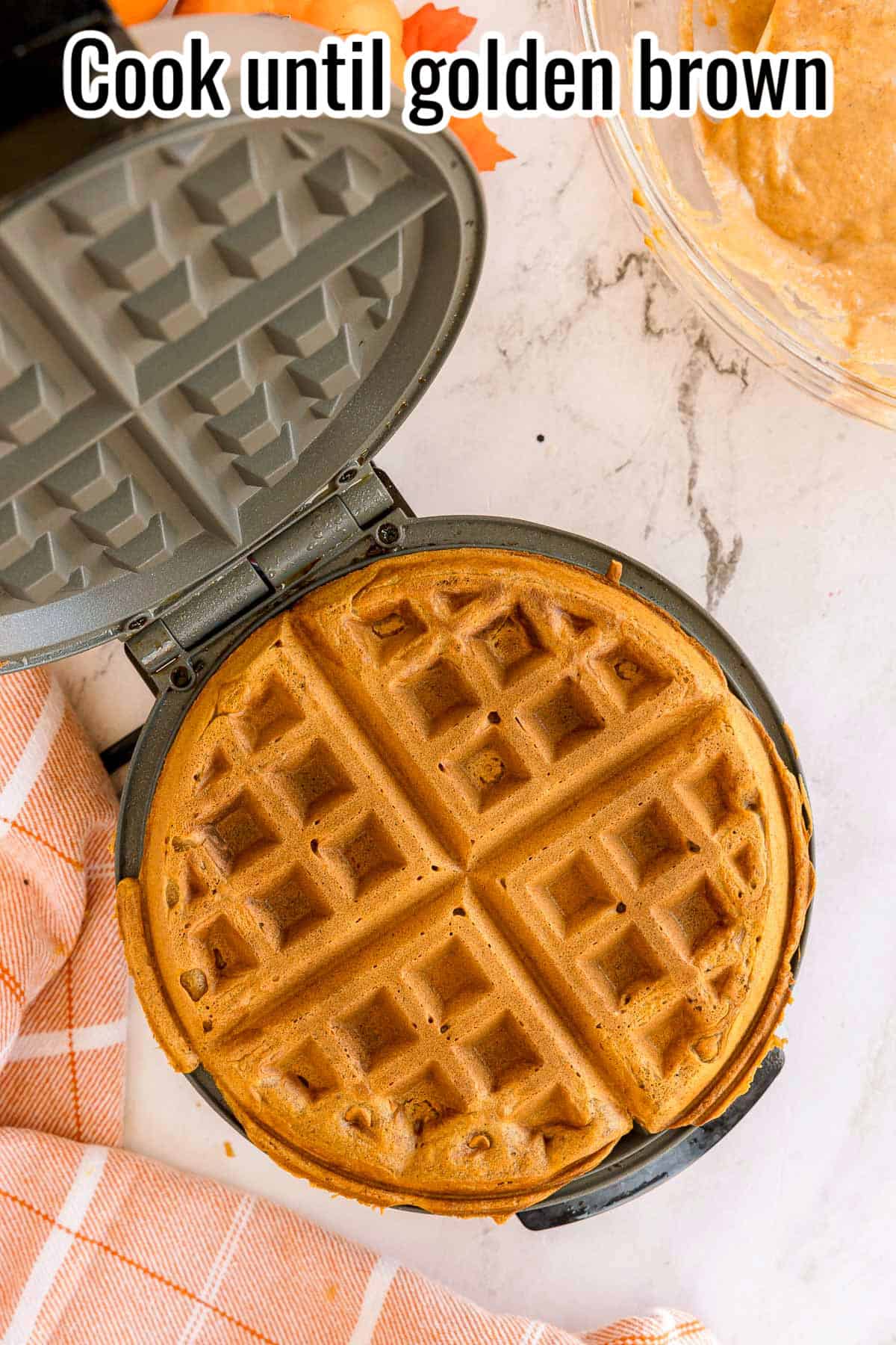 A golden brown waffle in the waffle iron. Text on the image says 'Cook until golden brown'.