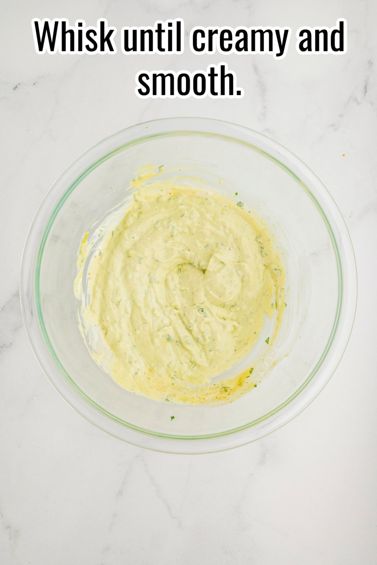 A bowl of creamy avocado dressing after whisking. Text on the image says 'Whisk until creamy and smooth.'.
