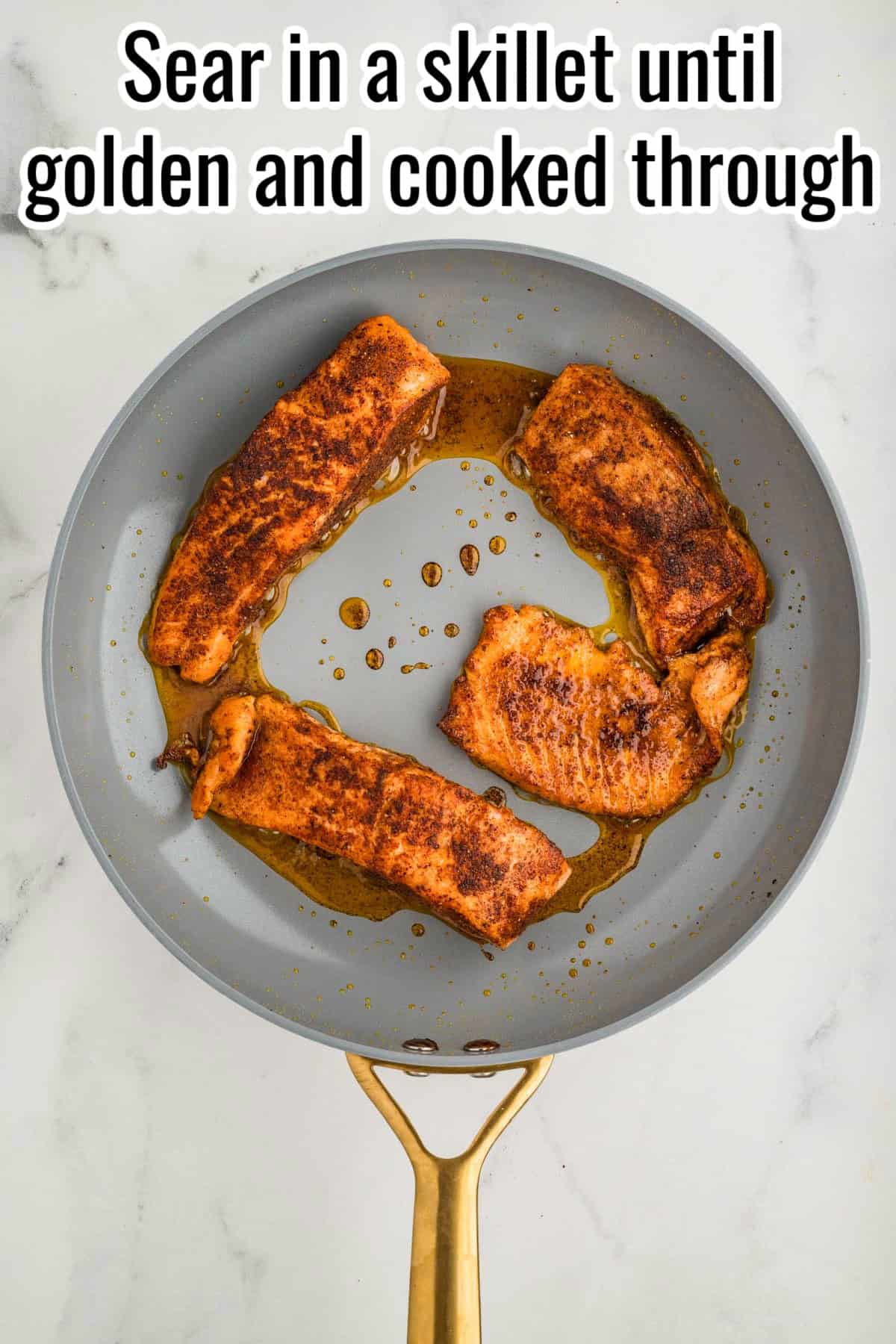 Salmon fillets searing in a skillet with oil. Text on the image says 'Sear in a skillet until golden and cooked through'.