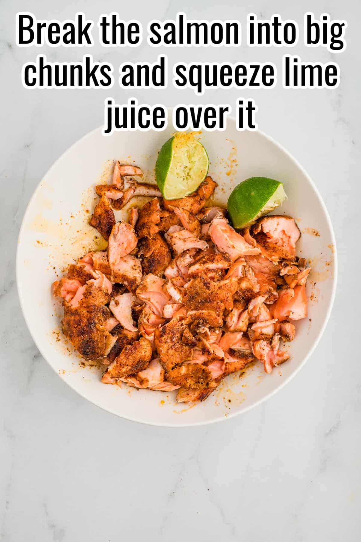 A bowl with flaked salmon and two squeezed lime halves. Text on the image says 'Break the salmon into big chunks and squeeze lime juice over it'.