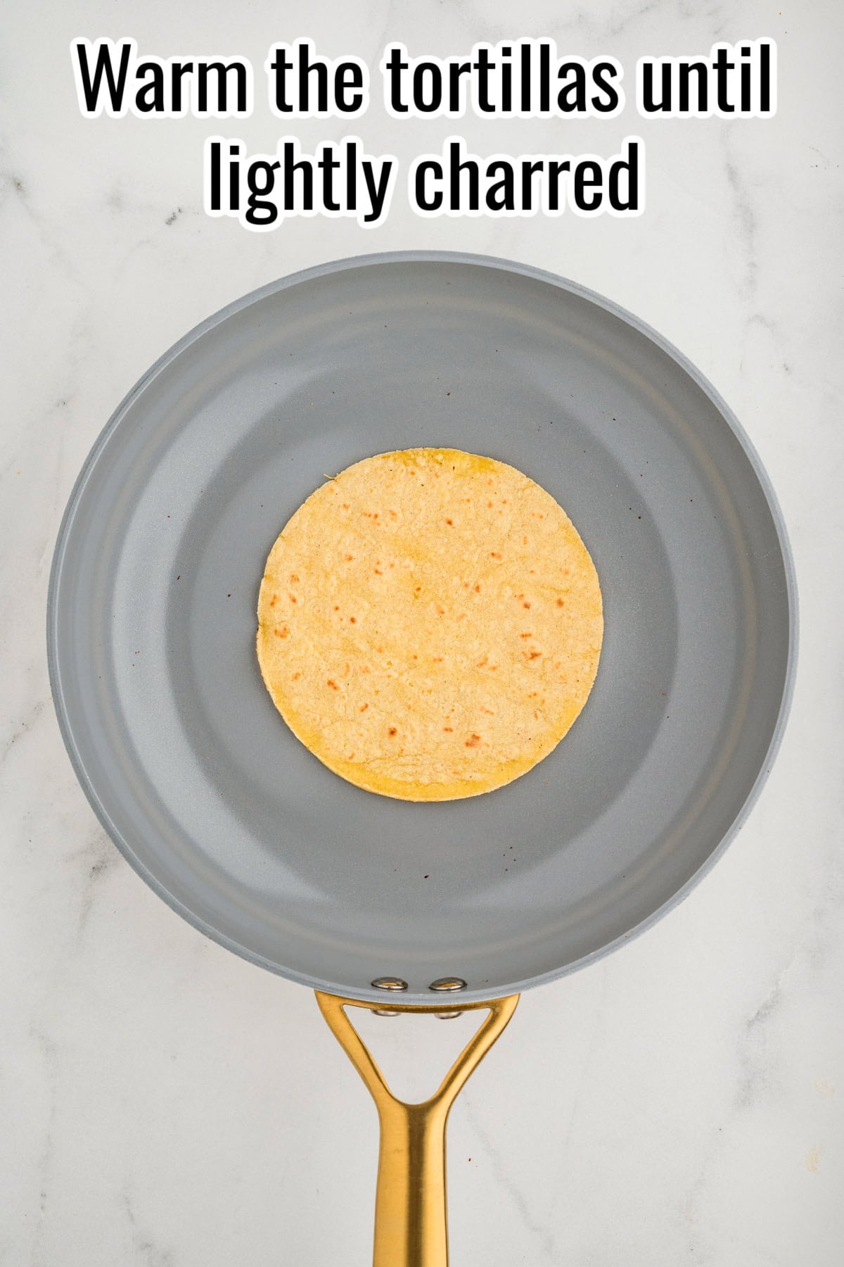 A tortilla warming in a skillet. Text on the image says 'Warm the tortillas until lightly charred'.
