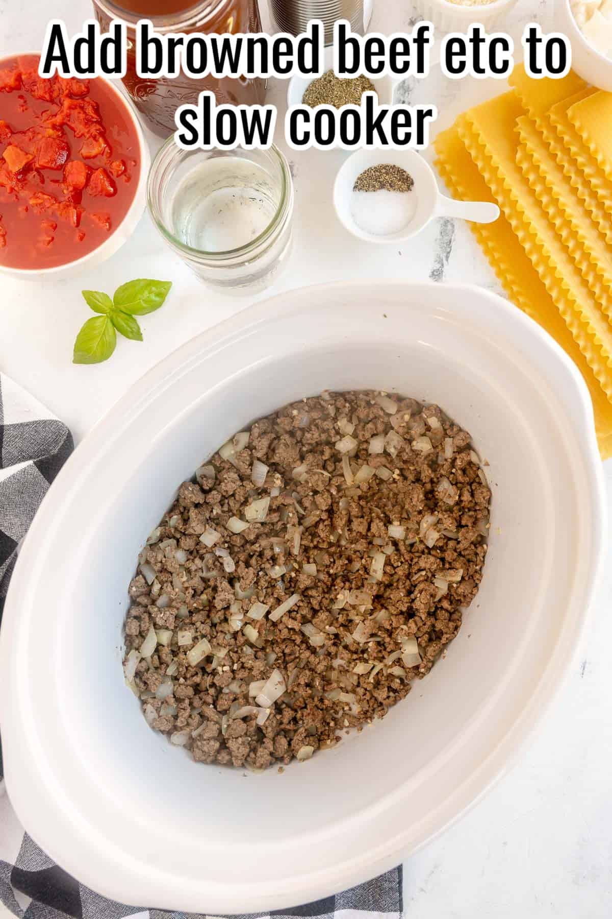 A slow cooker with browned beef, onions and garlic.
