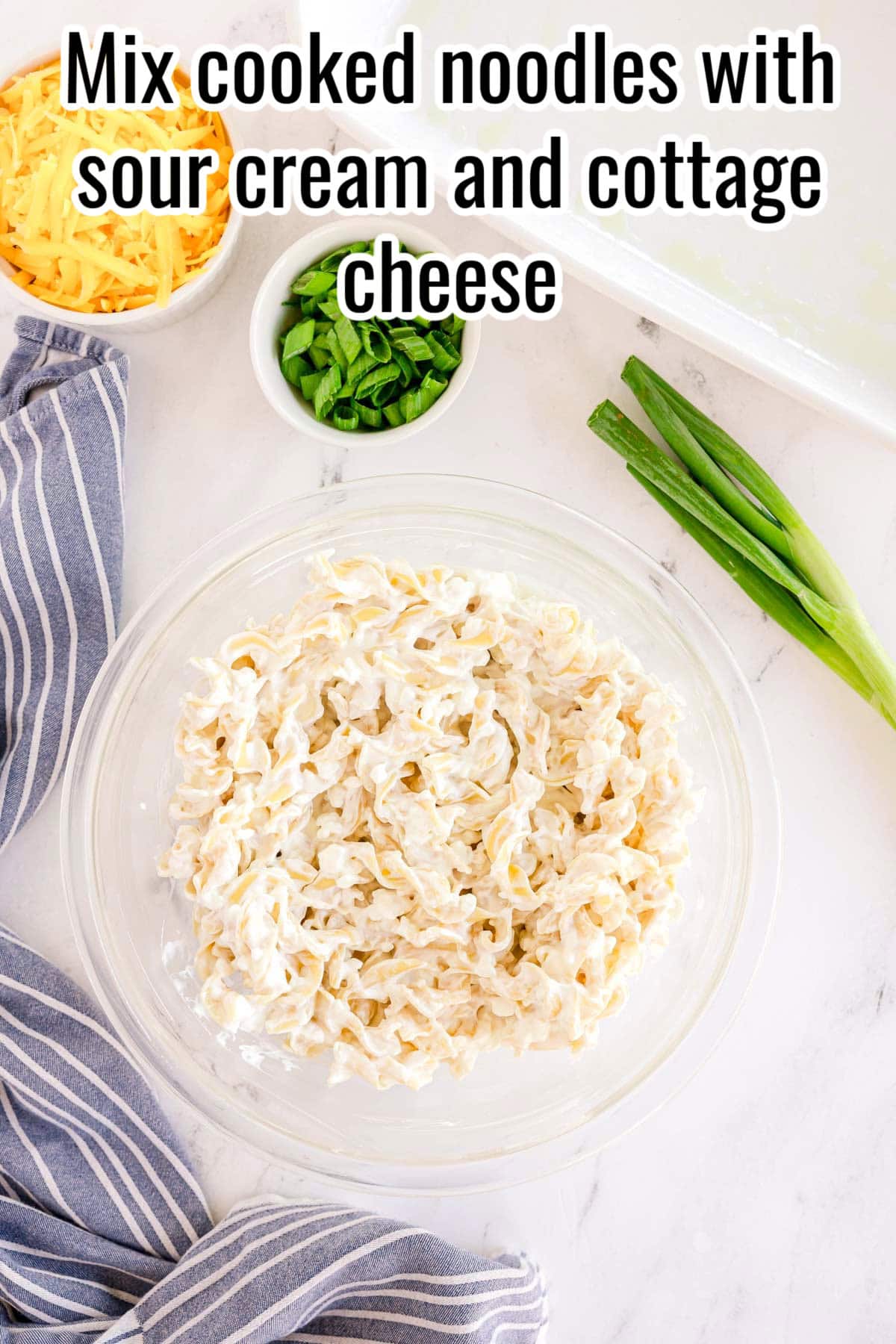 A bowl of egg noodles mixed with sour cream and cottage cheese. Text on the image says 'Mix cooked noodles with sour cream and cottage cheese'