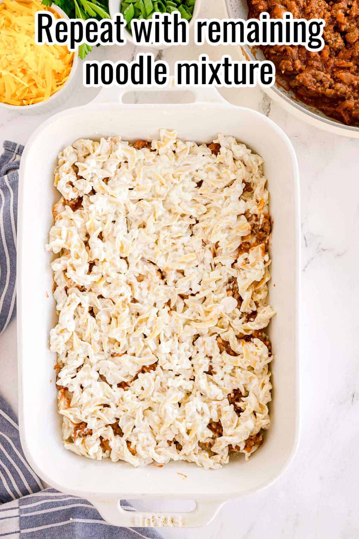 The second layer of creamy noodles added over the beef. Text on the image says 'Repeat with remaining noodle mixture'