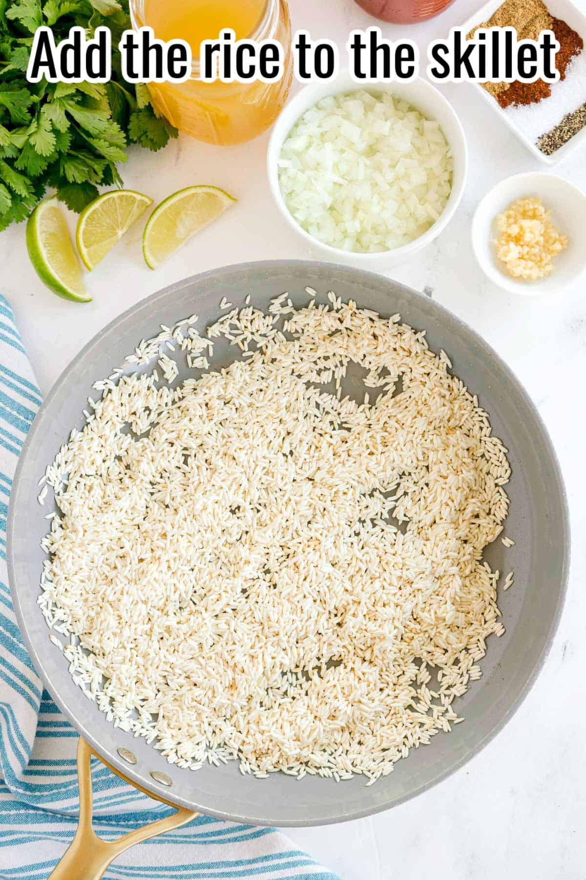 A skillet with uncooked rice, surrounded by chopped onions, garlic, lime wedges, and broth. Text on the image says 'Add the rice to the skillet'.