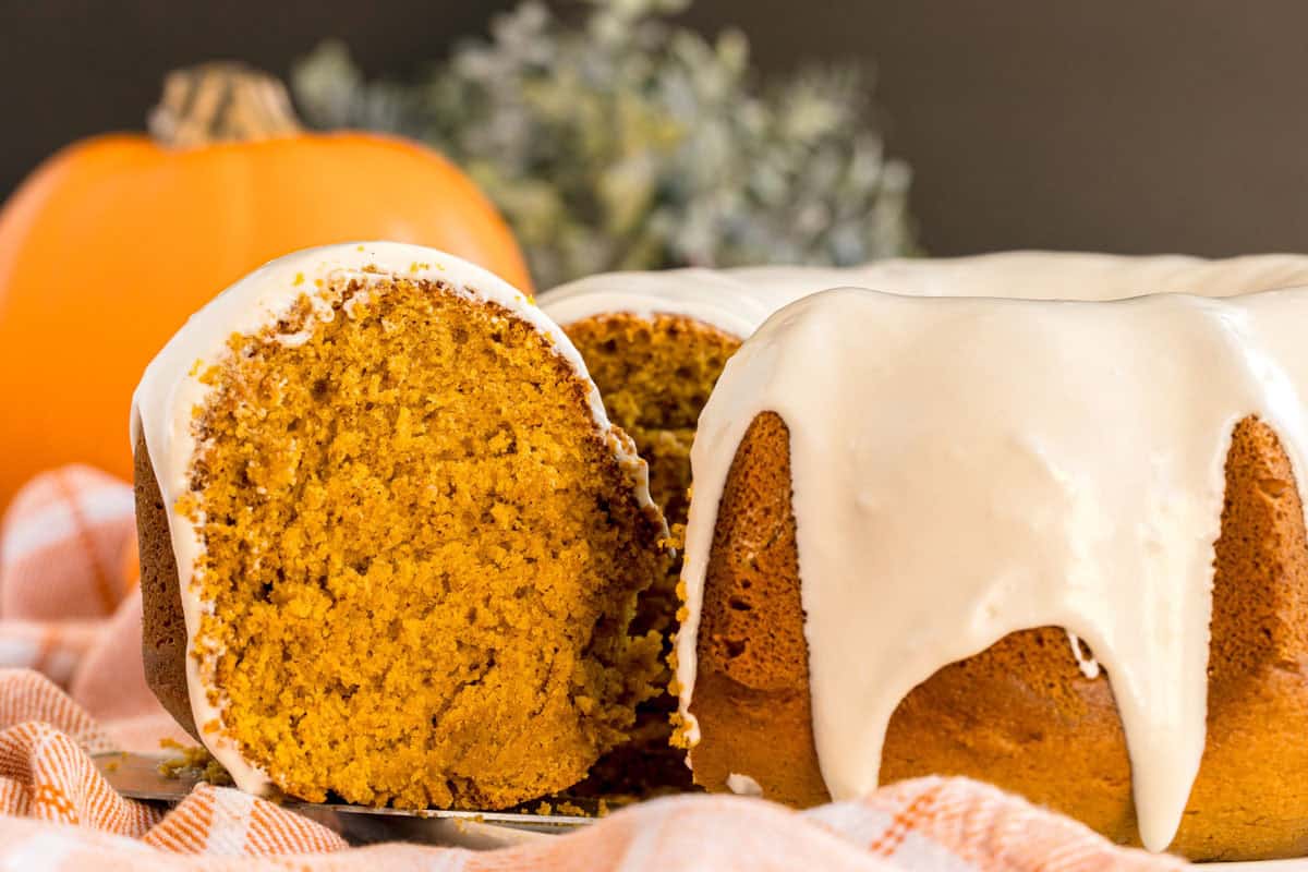 A pumpkin bundt cake with cream cheese glaze, missing a slice.