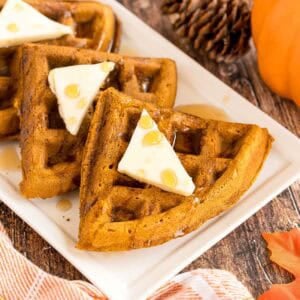 syrup being poured over a pumpkin spice waffle.
