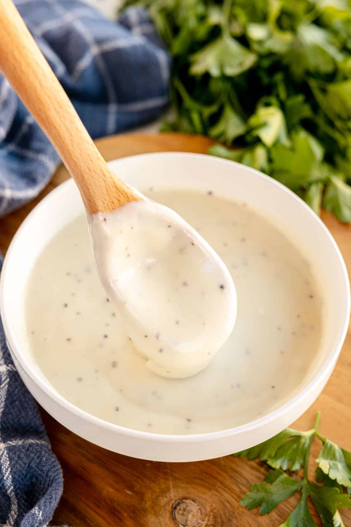 white sauce in a bowl with a wooden spoon.